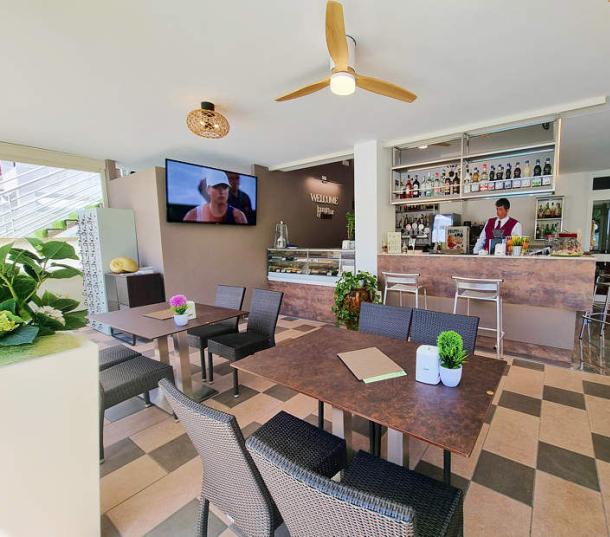 Moderne Bar mit Tischen, TV und gut bestückter Theke.