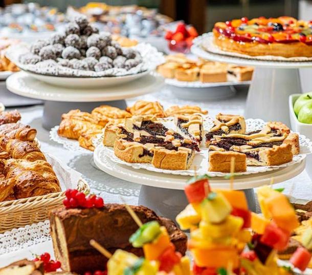 Buffet di dolci con torte, croissant e frutta.